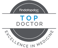 The image displays a stylized badge with the text  FINDATOP DOCTOR  at the top, followed by  TOP DOCTOR  in bold letters. Below this, there is an emblem indicating a challenge or competition, and further down, the words  CHALLENGE OF THE YEAR  are visible. The background of the badge features a blue circular design with a white border. At the bottom of the image, there s a graphic element resembling a doctor s stethoscope in black and white.