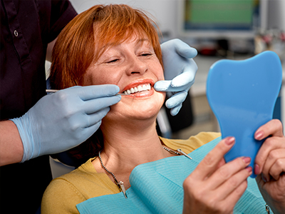 Woman in a dental chair with a blue dental tray, receiving a dental treatment.